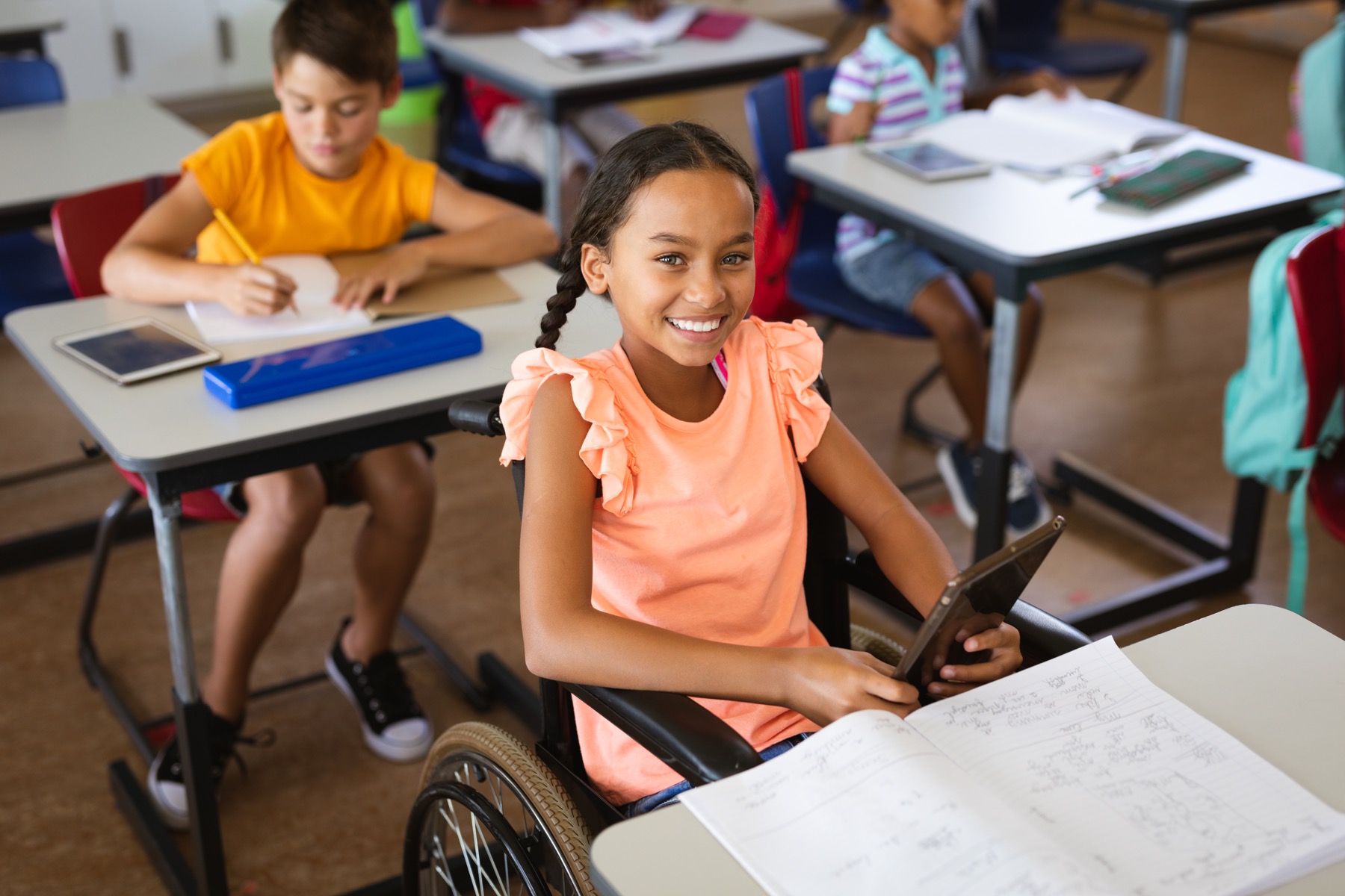 Smiling student using a wheelchair in a classroom